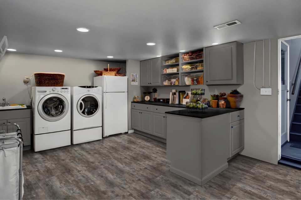 vinyl plank flooring in laundry room in downstairs kitchen with grey cabinetry